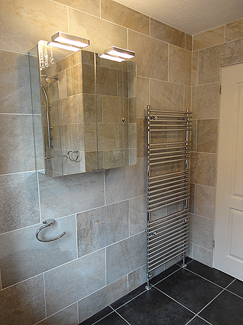The designer chrome towel warmer/radiator & mirrored bathroom cabinet with overhead lighting